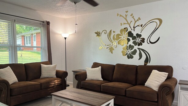Un salon avec deux canapés marron, une table basse blanche et une fresque murale décorative.