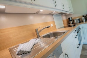 Eine moderne Küche mit Spüle aus Edelstahl, Holz Arbeitsplatte und weißen Schränken.