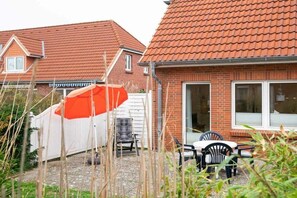 Ein Wohngebiet mit Ziegelhäusern, einem weißen Zaun und einer Terrasse mit Gartenmöbeln.