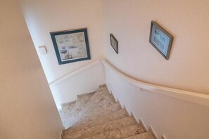 Uma escada com corrimão, uma parede com quadros e um interruptor de luz.