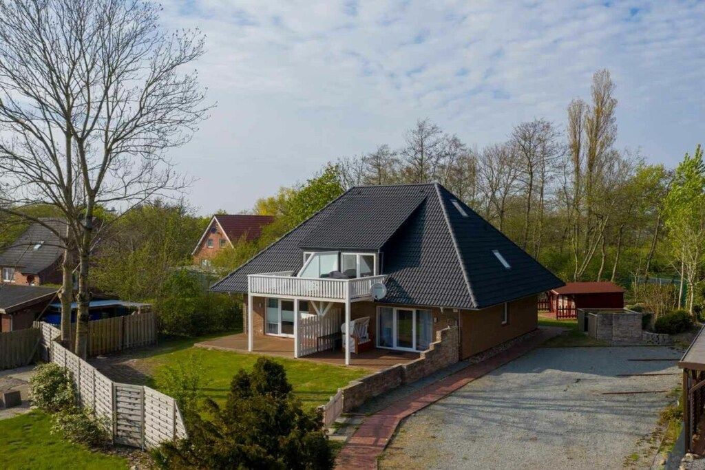 A two-story house with a balcony, a fenced yard, and a driveway.