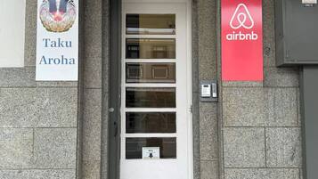 A building entrance with a white door, a mailbox, and two signs: one for Taku Aroha and another for Airbnb.
