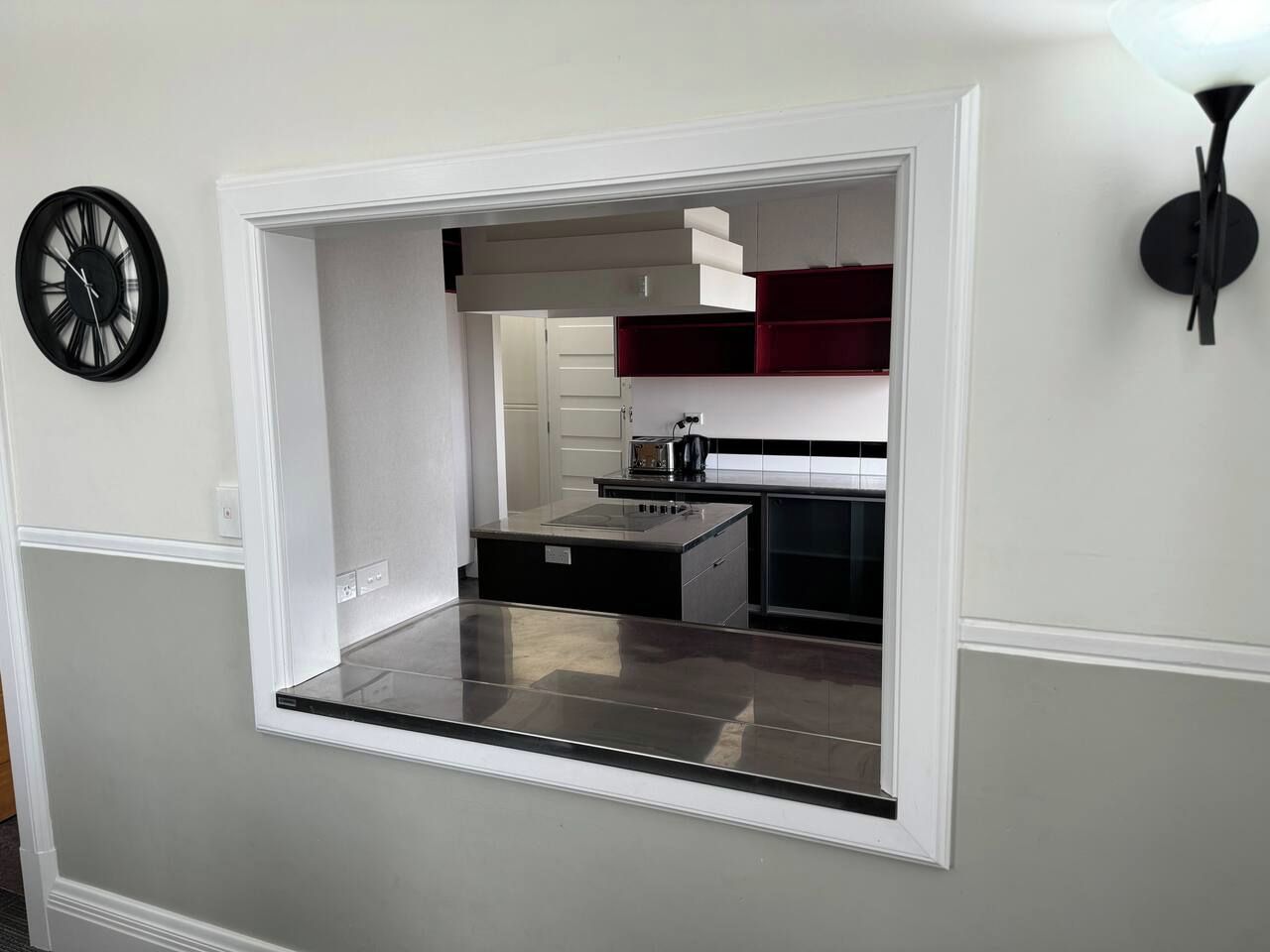 A modern kitchen with a built-in island, white cabinetry, and a black countertop.