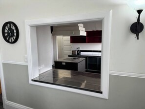A modern kitchen with a built-in island, white cabinetry, and a black countertop.