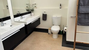 Een moderne badkamer met twee wasbakken, een toilet en een spiegel.