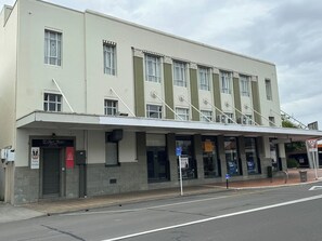 Un edificio con fachada plana, múltiples ventanas y un letrero que indica una propiedad en venta.