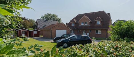 A residential property with a two-story brick house, a garage, and a car parked in the driveway.
