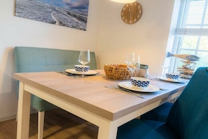 A dining table with a wooden top, two chairs, and a bowl of fruit. - Holiday apartment 5 "Gröde" (ID 474) (Tating)