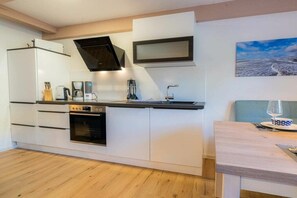 A compact kitchen with a built-in oven, a coffee maker, and a sink. - Holiday apartment 5 "Gröde" (ID 474) (Tating)