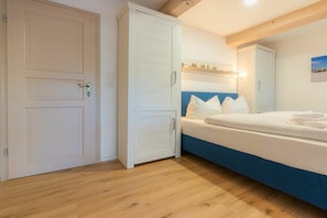 A bedroom with a bed, a wardrobe, and a door. - Holiday apartment 5 "Gröde" (ID 474) (Tating)