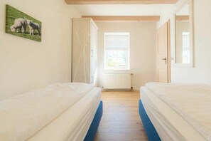 A bedroom with two beds, a window, and a radiator. - Holiday apartment 1 "Oland" (ID 470) (Tating)