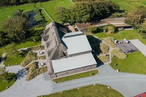 A large building with a sloped roof, surrounded by green fields and trees. - Holiday apartment 1 "Oland" (ID 470) (Tating)