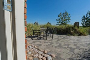 An outdoor patio with a table and chairs, surrounded by a brick wall and a grassy area. - Holiday apartment 1 "Oland" (ID 470) (Tating)
