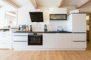 Eine moderne Küche mit weißen Schränken, einem eingebauten Backofen, einer Mikrowelle und einer Kaffeemaschine.