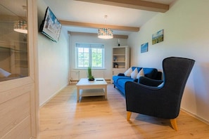 Ein modernes Wohnzimmer mit einer Couch, einem Sessel, einem Couchtisch und einem Fenster.