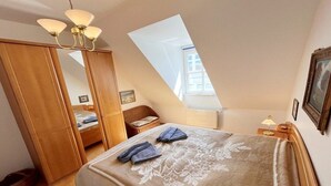 Una camera da letto con un letto, un'armadio in legno, un comodino e un lucernario.
