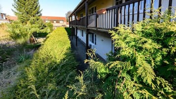 Ein Gebäude mit einem Balkon, umgeben von üppiger Vegetation und einem gepflegten Rasen.