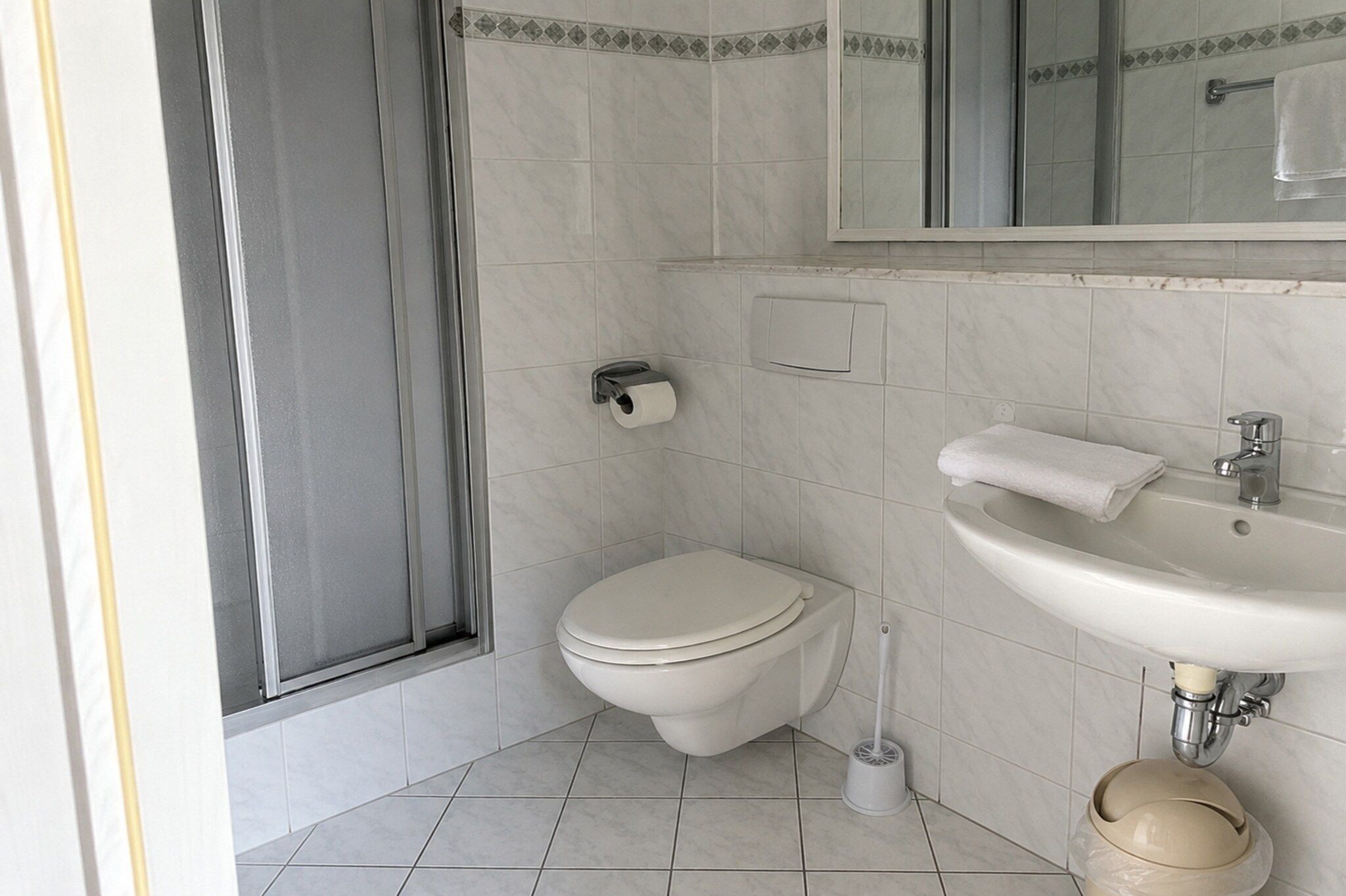 Een badkamer met toilet, wastafel en spiegel.