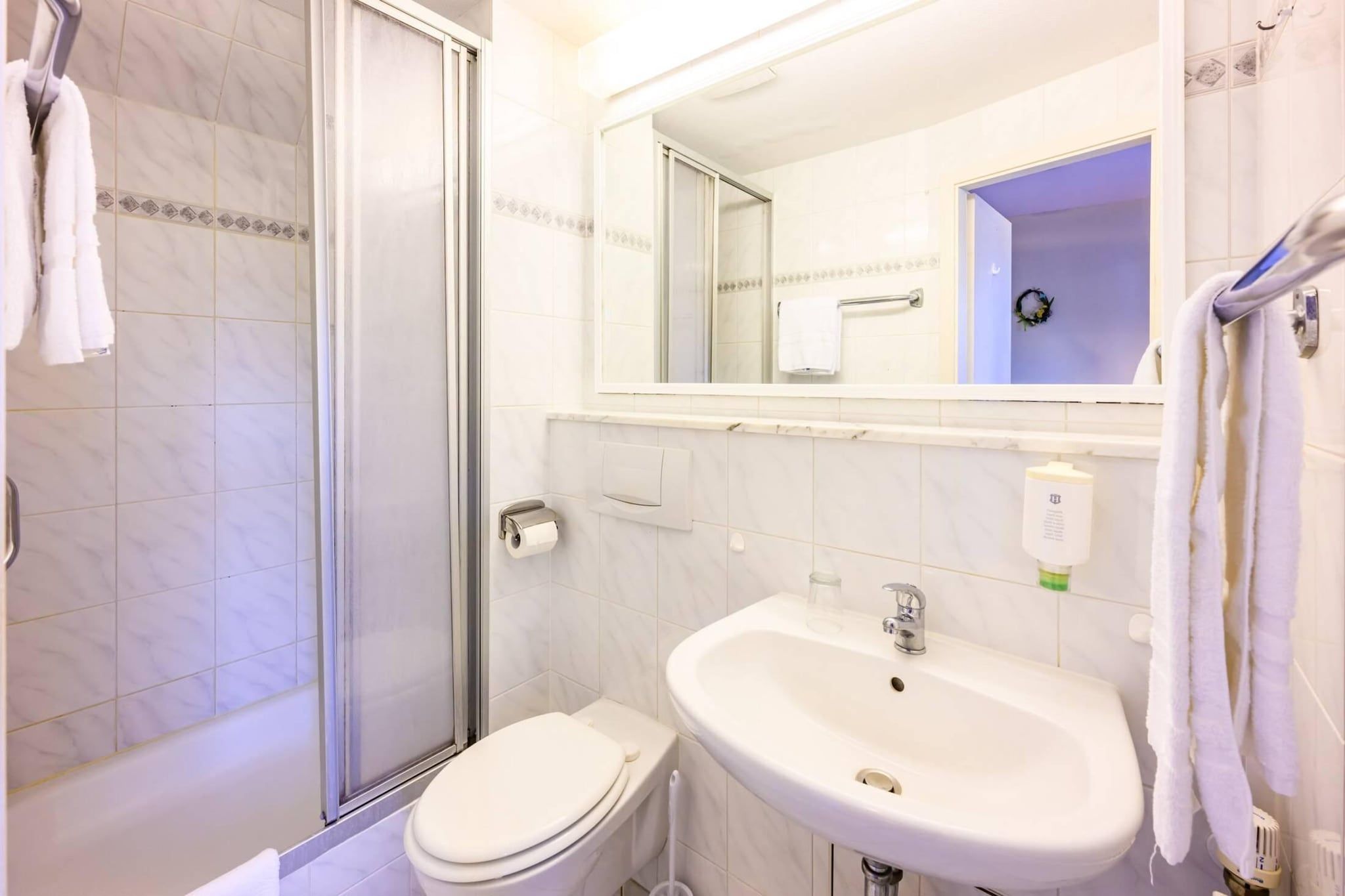 Ein Badezimmer mit Dusche, Toilette, Waschbecken und Spiegel.