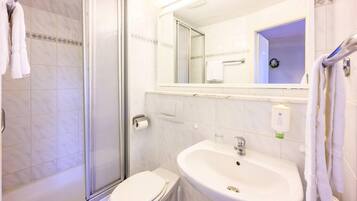 Ein Badezimmer mit Dusche, Toilette, Waschbecken und Spiegel.