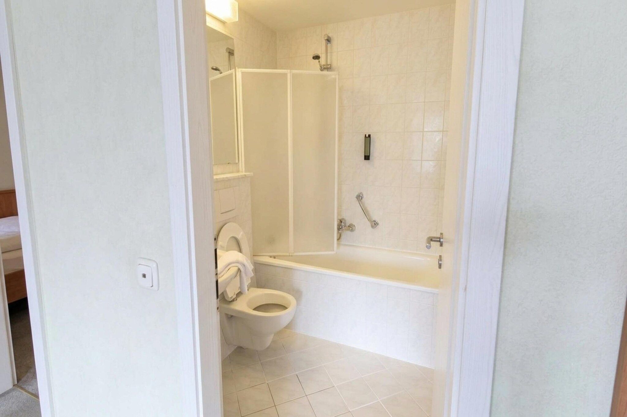 A bathroom with a toilet, a bathtub, and a shower area.