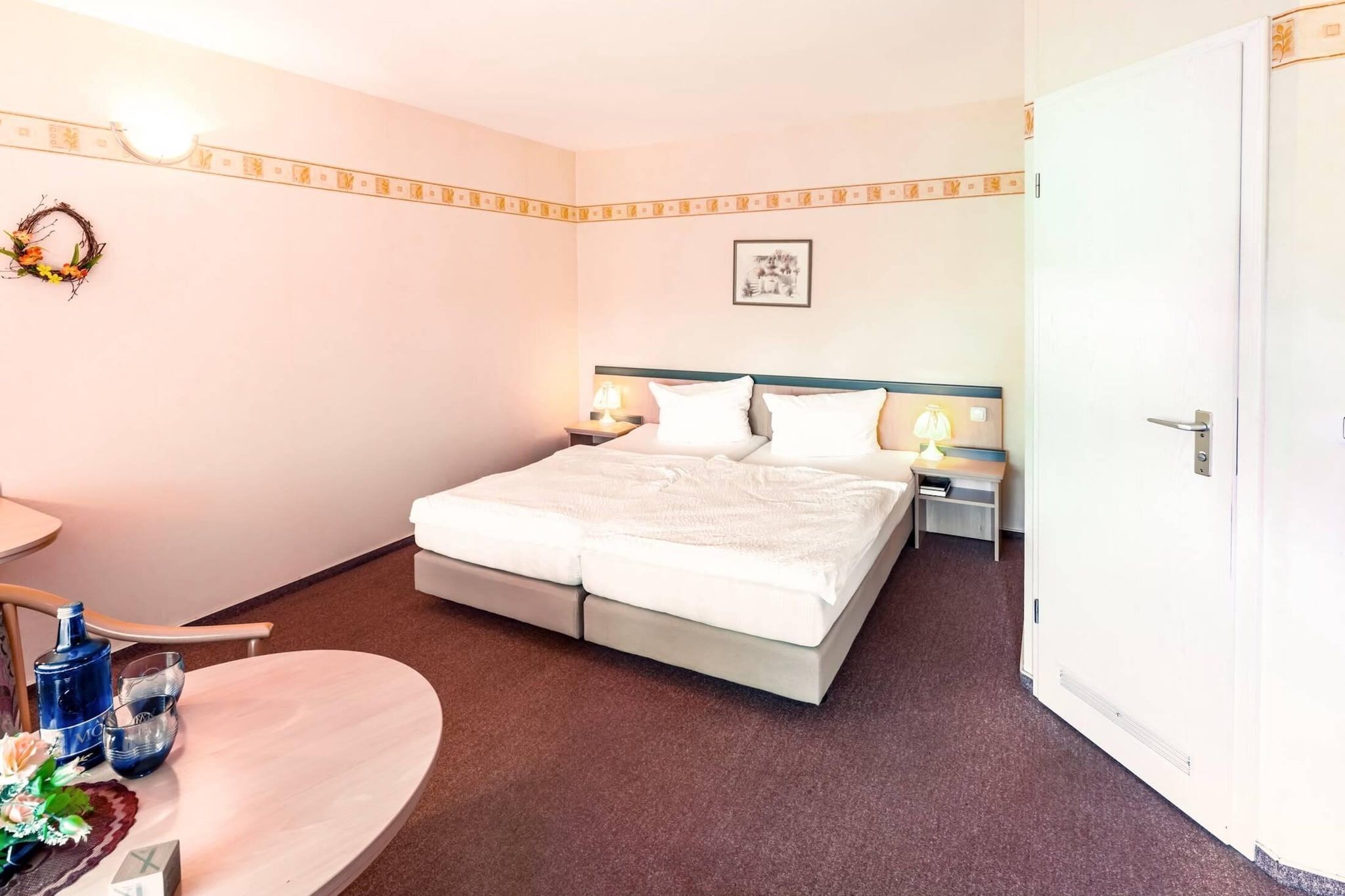 Ein Hotelzimmer mit Bett, Nachttischen, Schreibtisch und Stuhl.