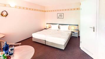 Ein Hotelzimmer mit Bett, Nachttischen, Schreibtisch und Stuhl.