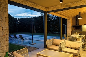 Pátio externo com área de estar, mesa posta para refeições e vista da paisagem ao redor.