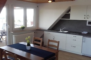 A compact kitchen with white cabinets, a black countertop, and a window with a view of buildings. - Bernhard Winery Type A (Daisendorf)