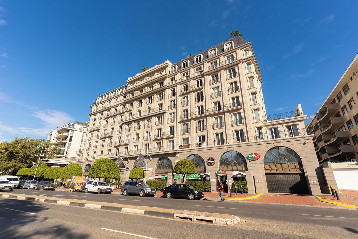 A multi-story hotel with a classic architectural style, featuring a central entrance with a large arched doorway and a series of balconies.