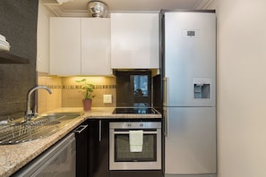 A compact kitchen with stainless steel appliances, a built-in oven, and a water dispenser. - Cape Royale 1BR Apt with Parking & Pool (Cape Town)