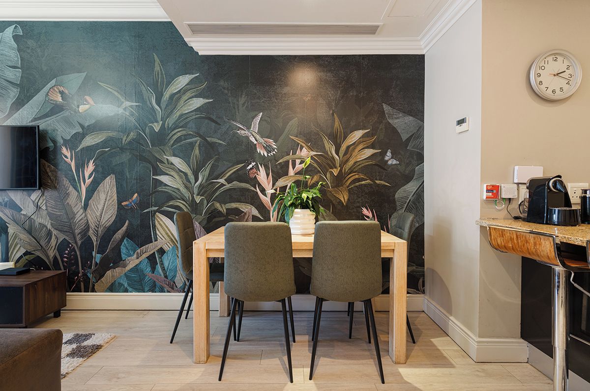 A dining area with a mural, a clock, and a coffee machine.
