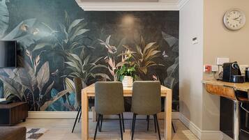 A dining area with a mural, a clock, and a coffee machine.