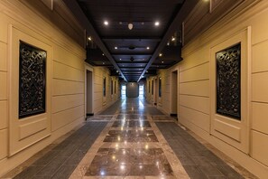 A long, narrow hotel corridor with a reflective tiled floor and decorative metal panels on the walls. - Cape Royale 1BR Apt with Parking & Pool (Cape Town)