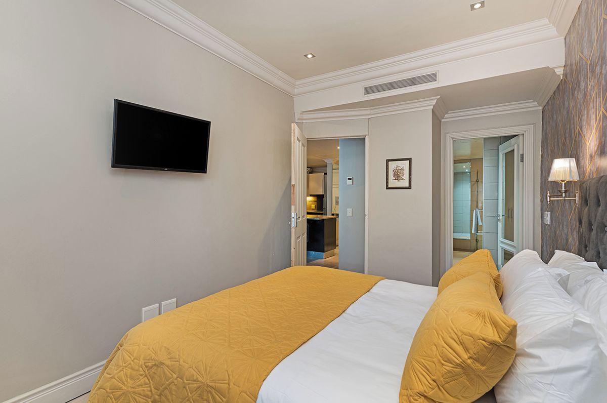 A hotel room with a bed, a television mounted on the wall, and a bathroom visible through an open door.
