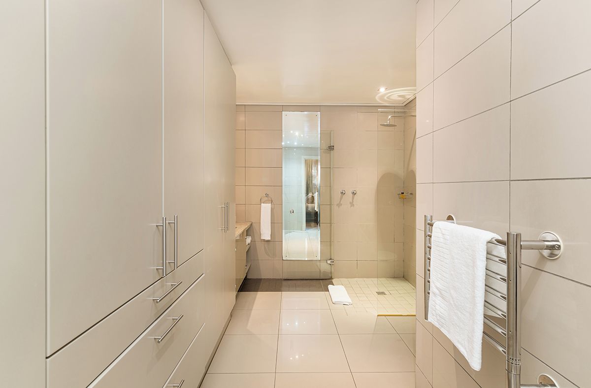 A modern bathroom with a walk-in shower, a glass door mirror, and a towel rack.