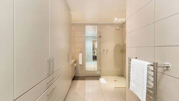 Een moderne badkamer met een ruime douche, een spiegel met glazen deur en een handdoekhouder.