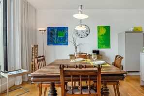 Ein Essbereich mit einem Holztisch, Stühlen, einer Uhr und Kunstwerken an den Wänden.