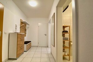 Un couloir avec une armoire en bois, une porte blanche et une étagère où sont posées des serviettes.