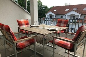 An outdoor patio with a wooden table and four chairs, each with a red cushion. - ||---------------------------------at the hop garden---------------------|| (Lindau)
