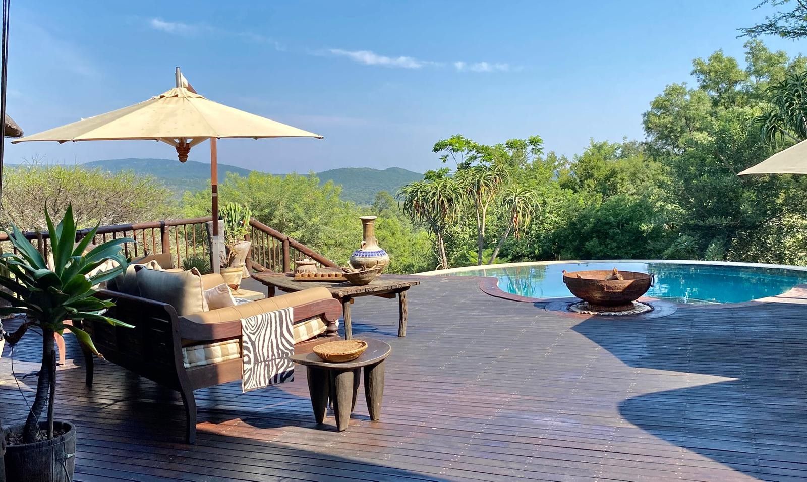 A wooden deck with outdoor furniture, a pool, and a view of the surrounding landscape.