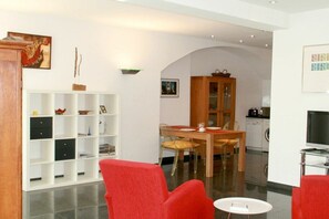 A modern living room with a dining area, white walls, and a kitchen in the background. - Holiday apartment LiLi 10 (Lindau)