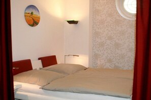 A bedroom with a bed, a wall-mounted lamp, and a window with a view of the outdoors. - Holiday apartment LiLi 10 (Lindau)