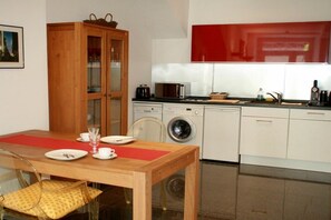 A compact kitchen with a wooden cabinet, a washing machine, and a microwave. - Holiday apartment LiLi 10 (Lindau)