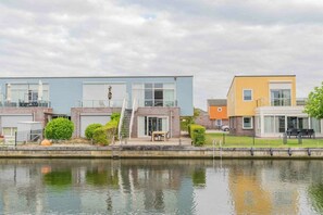 A row of modern houses by a calm water body, with a clear sky above. - Holiday home with 1 bedroom (Oude-Tonge)