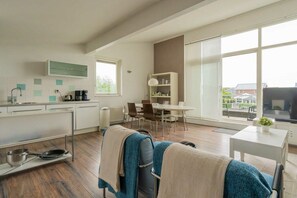 A modern kitchen with a dining area, large windows, and a view of the outside. - Holiday home with 1 bedroom (Oude-Tonge)