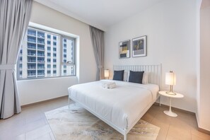 A modern hotel bedroom with a large bed, two bedside lamps, a view of a building through the window, and a rug on the floor. - Homey 2 Bed l Dubai Hills Mall within Community (Dubai Hills)
