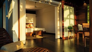 A modern bedroom with a bed, bedside table, and a view of the outside. - Nanmah Beach Resort (Ambalapuzha)