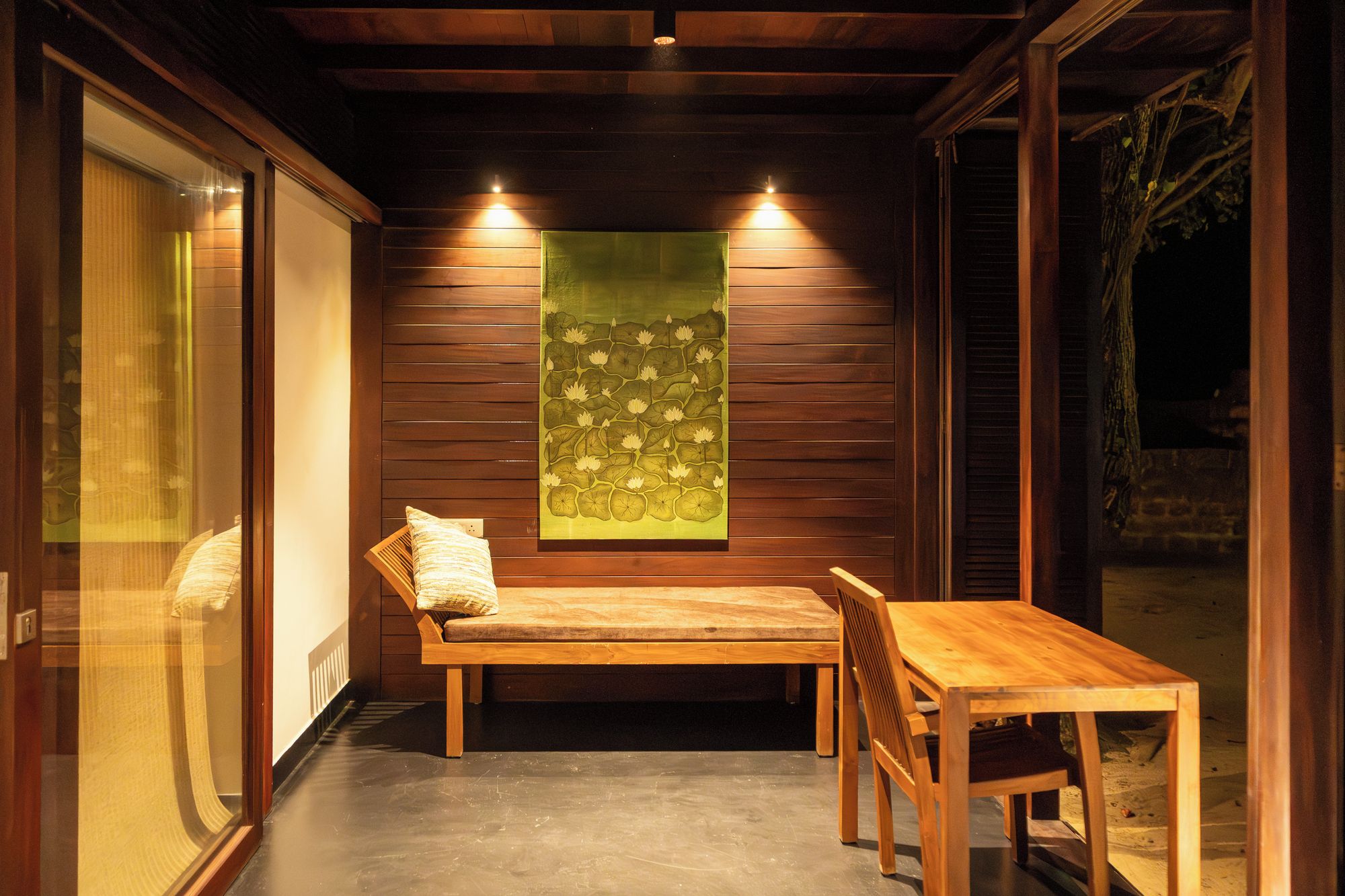Un conjunto de banco y mesa de madera en una habitación con paneles de madera y una obra de arte verde.