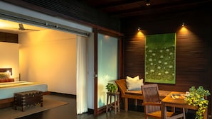 Quarto de hotel moderno com cama, escrivaninha e área de refeições.